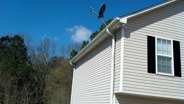 Pro Gutter Cleaning and Repair — new white gutter on a beige-sided two-story home with a weathervane on the roofline