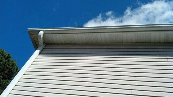 Pro Gutter Cleaning and Repair — white gutter corner and downspout cleanly finished on a cream-siding ranch home
