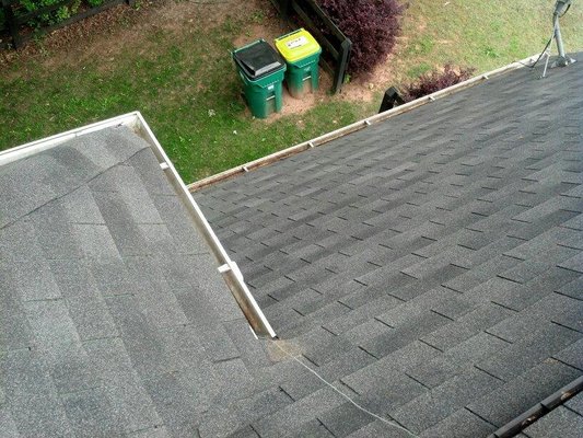 Pro Gutter Cleaning and Repair — aerial view of a roof line with shingles and gutter section, service ladder and bins visible below
