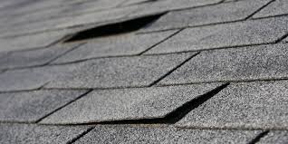 Pro Gutter Cleaning and Repair — close-up of curled and wind-damaged asphalt shingles ready for roof repair